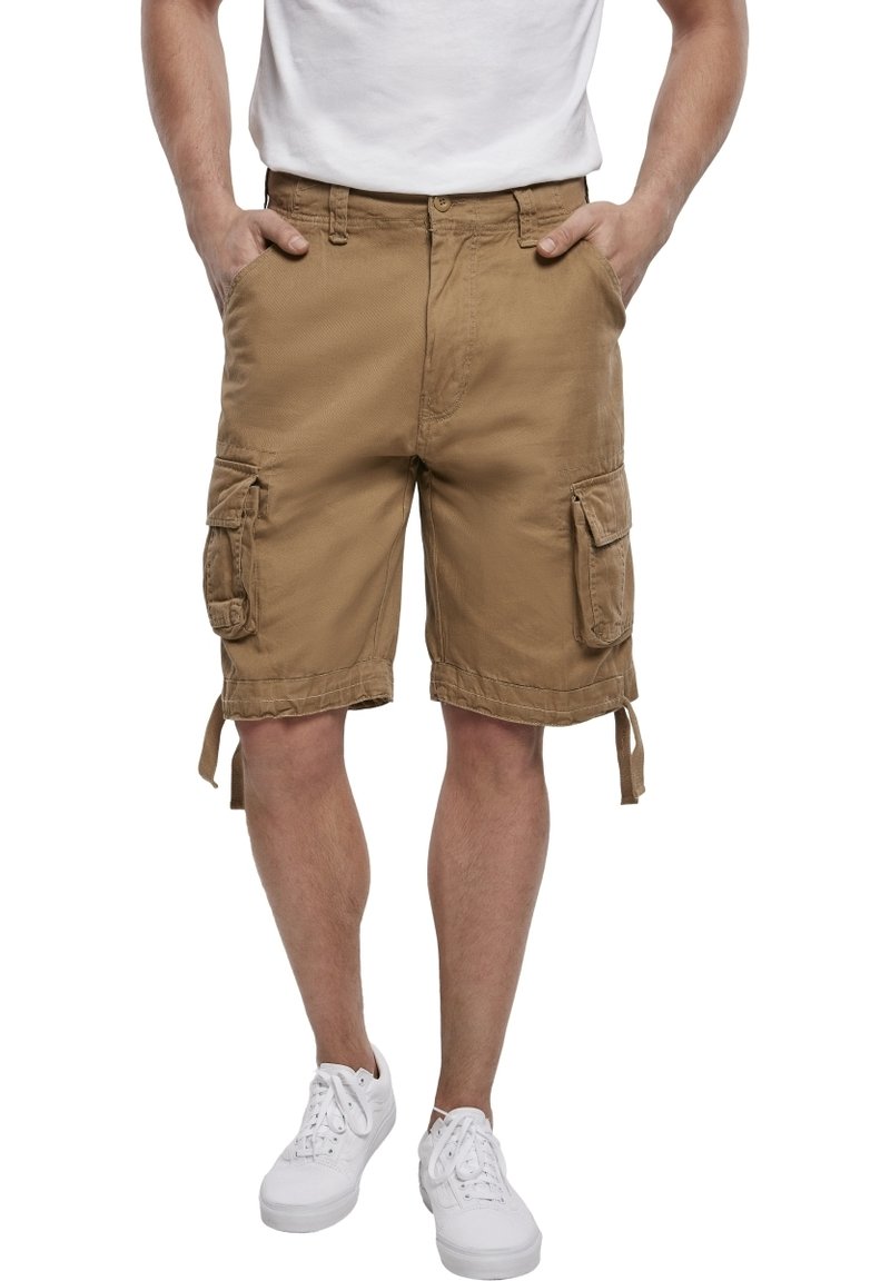 Shorts cargo beiges, fabriqués en tissu durable avec plusieurs poches, ourlets noués et coupe décontractée. Associés à des baskets blanches.