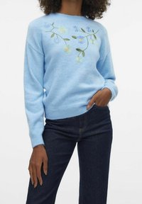Light blue sweater made of soft fabric, featuring floral embroidery in blue, yellow, and green. Ribbed cuffs and hem, relaxed fit.