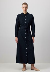 Jūras zila garo piedurkņu kleita, kas izgatavota no teksturētas auduma, ar pogu priekšpusi, kakla, jostu viduklim un dekoratīvām zilām pogām.