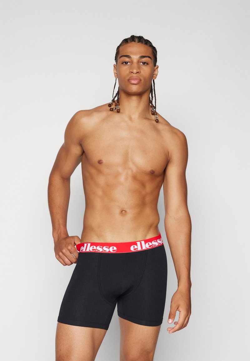 Svarta boxershorts med en röd "ellesse"-logotyp på midjebandet, slät tygkvalitet, kroppsnära passform och längd till mitten av låret.