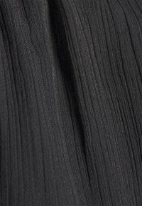 Svart veckad tyg med vertikala linjer, lättviktsmaterial och en slät yta, lämplig för olika plagg och designer.