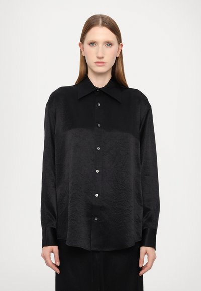 Chemise noire à manches longues avec une texture froissée, dotée d'un col pointu et d'une fermeture à boutons sur le devant ; coupe décontractée.