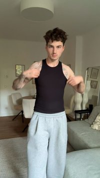 Musthave muströöpidega must ilma varrukateta T-särk, mis on sobitatud hallide dressipükstega, heledas siseruumis.