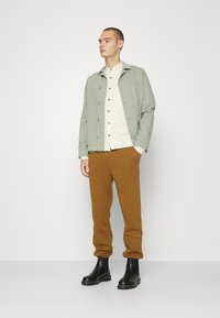 Jack & Jones JJIKANE JJBRINK PANTS - Calças de fato de treino - desert palm