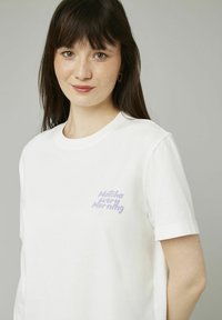 T-shirt en coton blanc avec un graphique violet clair portant l'inscription "Matcha chaque matin." Col rond classique et coupe décontractée.