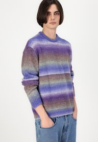 Gehaakt vest in paarse, blauwe en aardse tinten met een gestreept patroon, ronde halslijn en ribgebreide mouwen. Gemaakt van een zachte, gestructureerde stof.