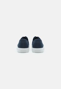 Baskets en toile navy avec un design bas, semelles en caoutchouc blanches et détails de couture subtils le long de l'arrière et des côtés.