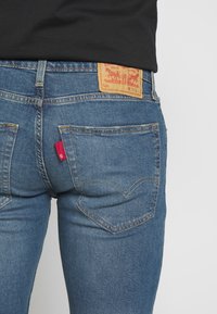 Blaue Jeans aus Denim mit leicht ausgewaschenem Finish. Verfügt über ein braunes Lederetikett am Bund und ein rotes Label an der Gesäßtasche.
