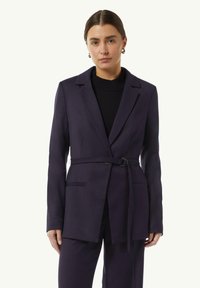Granatowa marynarka z paskiem w talii, z pojedynczym zapięciem na guzik i dwoma przednimi kieszeniami. Gładki materiał z dopasowanym krojem i klapami w stylu notch.