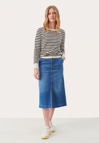 Maglione a maniche lunghe a righe in crema e blu navy, abbinato a una gonna di jeans blu a vita alta. Sneakers bianche casual completano il look.