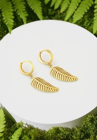 Orecchini color oro con un design a foglia caratterizzato da intricate aperture e una chiusura a cerchio. Esposti su un piedistallo circolare bianco.