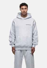 Felpa grigia in cotone con tasca frontale, cappuccio con coulisse e la scritta "GOODFORNOTHING" stampata sul petto. Maniche lunghe con polsini a coste.