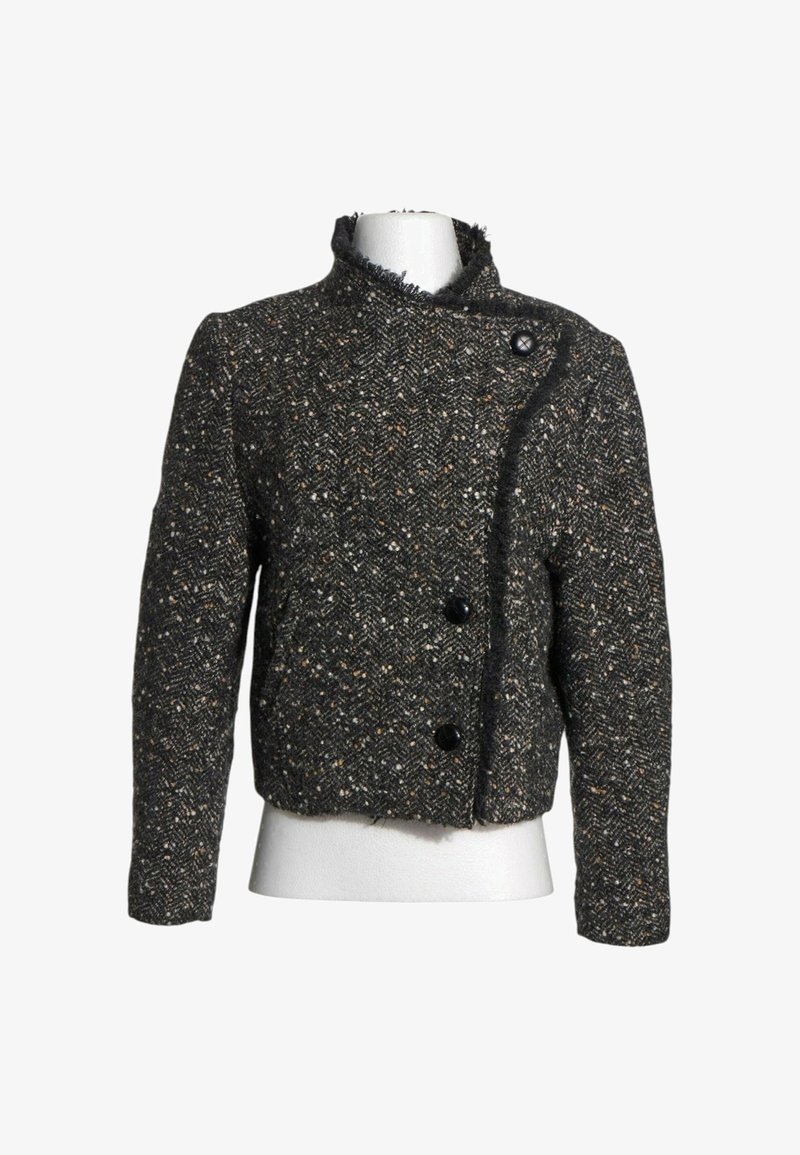 Veste en laine texturée gris foncé avec trois boutons noirs et bords effilochés sur un buste de mannequin blanc.