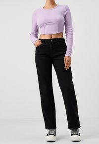 Lavendelrandig långärmad croppad topp som är matchad med högmidjade svarta vida jeans och svartvita snörskor.