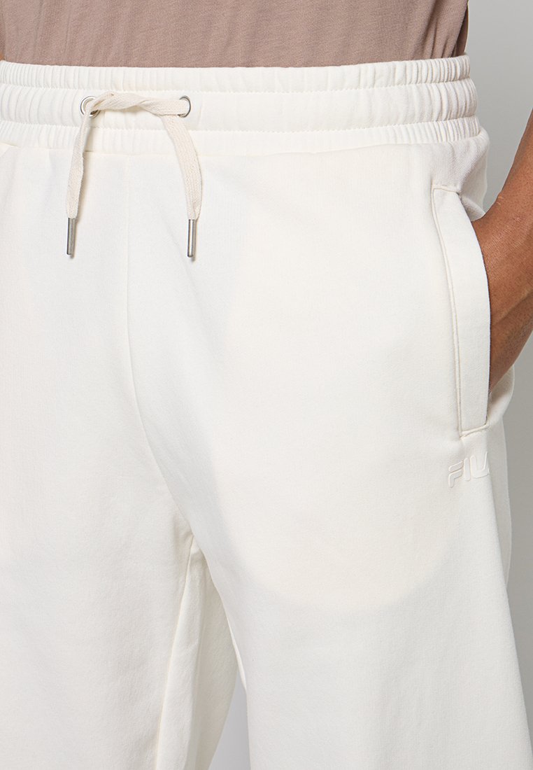 Pantalones deportivos blancos con cintura elástica y cordón. Bolsillos laterales y detalle de logo bordado. Material suave con una textura lisa.