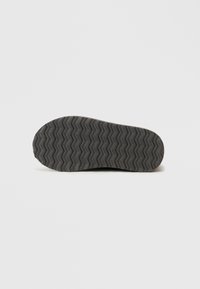 Rubber shoe sole with a textured zigzag pattern, black color, rounded shape, and smooth edges. No visible branding or additional details.
