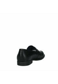 Zapato de cuero negro con punta redondeada, tacón bajo y correa ajustable en la parte superior. Textura suave y diseño simple sin patrones visibles.
