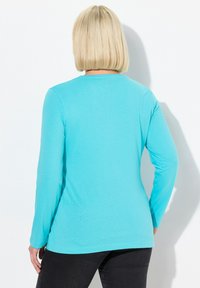 Langarmshirt aus lebhaftem Türkisstoff mit rundem Ausschnitt und glatter Textur. Einfaches Design mit lockerer Passform.