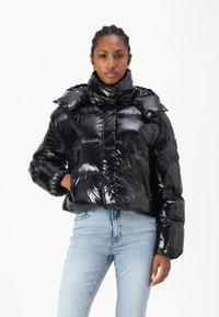 Mustmust must jacket läikiva viimistlusega, kõrge kraega, polsterdatud disainiga ja soonikute äärtega. Kanda helesiniste teksadega.