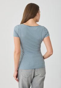 Zila svītrota T-krekls ar īsām piedurknēm un apaļu kakla izgriezumu, izgatavots no mīkstas auduma. Aizmugure demonstrē pieguļošu dizainu un smalku tekstūru.