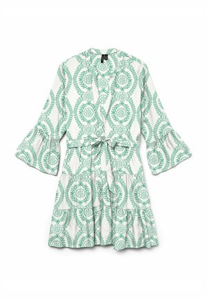Gepubliceerd wikkeljurk met een groen bladontwerp op een witte stof. Uitlopende mouwen en een strikdetail bij de taille maken het ontwerp compleet.
