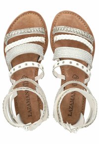 Sandales blanches en cuir avec plusieurs brides, ornées de clous en argent et d'accents tressés. Semelle intérieure rembourrée marron avec détail du logo.