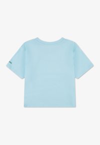 Φωτεινό γαλάζιο βαμβακερό t-shirt με στρογγυλή λαιμόκοψη και κοντά μανίκια, με απλό σχέδιο και μικρό πράσινο λογότυπο στο αριστερό μανίκι.