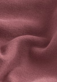Tessuto lavorato a maglia di colore rosa tenue, che mostra una texture morbida con un modello fine e uniforme e una leggera elasticità, creando pieghe delicate.