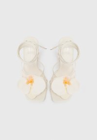 Sandali alti bianchi con cinturini e punta quadrata, caratterizzati da una grande orchidea artificiale bianca con un centro pesca sul dorso.