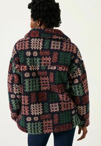 Fleecejacke mit einem Patchworkdesign in Marineblau, Grün, Rot und Beige; übergroßer Kragen und lockere Passform mit weicher Textur.