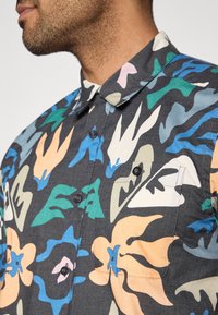 Κοντομάνικο πουκάμισο με σκούρο φόντο και αφηρημένα λουλουδένια σχέδια σε πορτοκαλί, μπ λε, πράσινο και ροζ. Κουμπιά στο μπροστινό μέρος.