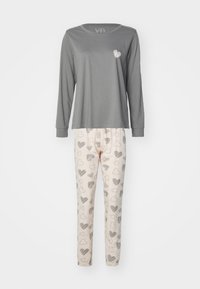 Långärmad grå pyjamasöverdel med en liten hjärtdesign; ihop med krämfärgade byxor med svarta hjärtan och elastisk midja.