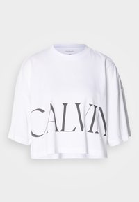 White cropped t-shirt made of cotton, featuring bold black lettering "CALVIN" across the front. Short sleeves and a relaxed fit.