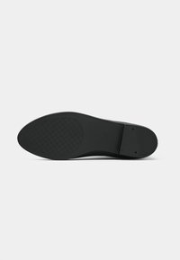 Sola de sapato de borracha preta com um padrão de aderência texturizado, bordas suaves e uma ligeira curvatura no calcanhar para suporte ergonómico.