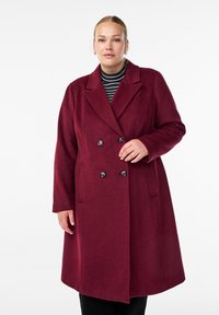 Bordo kabát z vlněné směsi s dvouřadým zapínáním, klopovými límci, dvěma bočními kapsami a černými knoflíky. Dlouhé rukávy, délka ke kolenům.