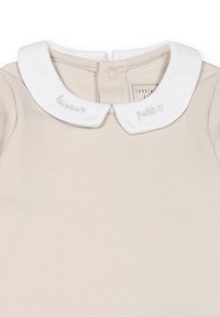 Indumento in cotone beige con colletto bianco. Il colletto presenta del testo ricamato con le parole "bonjour" e "petit" in un colore chiaro e sottile.