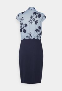 Haut à motif floral bleu avec une jupe ajustée bleu marine foncé. Le matériau est lisse ; le design présente une taille froncée et des manches courtes à empiècement.