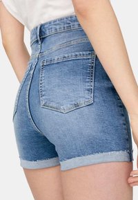 Höga denimshorts i en ljusblå tvätt med uppvikt fåll, med två bakfickor och en slät yta.