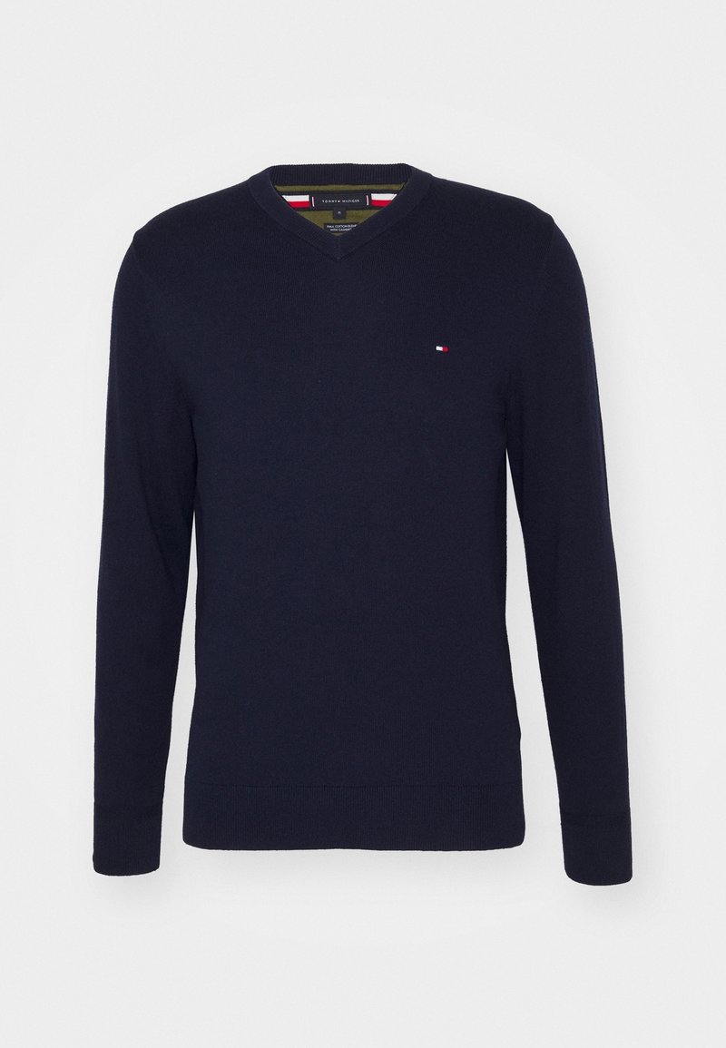 Pull bleu marine à manches longues avec col en V, petit logo rouge, blanc et bleu sur la poitrine gauche, poignets et base côtelés.