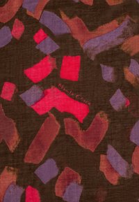 Tissu présentant des formes abstraites rouges, roses et violettes sur un fond marron foncé. Le logo "Manila Grace" est visible dans le design.