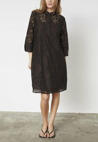 Sorte lace kjole med krave, knaplukning, trekvartærmer og mønstret tekstur, der inkluderer gennemsigtige sektioner og en løs pasform.