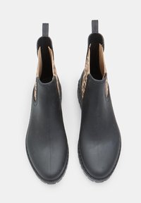 Botas Chelsea de goma negras con acentos de elastico con estampado de leopardo y tirador en la parte posterior. Textura suave y diseño de punta redonda.