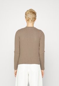 Brun ribbestrikket genser med lange ermer og rund hals. Har en smal passform og teksturert mønster, vist fra baksiden.