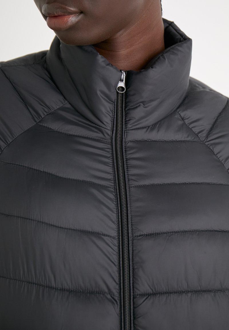 Chaqueta negra acolchada con cuello alzado, que presenta un diseño acolchado y un cierre frontal con cremallera. Textura suave y forma ajustada y elegante.