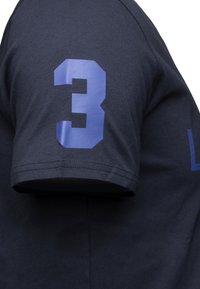 Czarny t-shirt w kolorze ciemnego granatu z dużą, kanciastą niebieską cyfrą "3" nadrukowaną na lewym rękawie, z klasycznym okrągłym dekoltem i krótkimi rękawami.