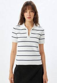 Witte geribbelde polo shirt met korte mouwen, voorzien van marineblauwe horizontale strepen en een notch-kraag, met een getailleerd ontwerp en een zachte textuur.
