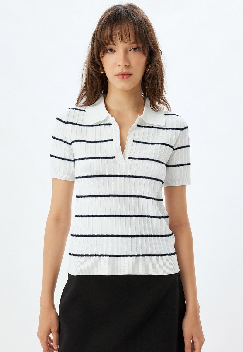 Witte geribbelde polo shirt met korte mouwen, voorzien van marineblauwe horizontale strepen en een notch-kraag, met een getailleerd ontwerp en een zachte textuur.