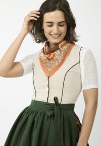 Leinenoberteil mit Knopfverschluss, cremefarbig, kombiniert mit einem grünen Rock. Ein florales orangfarbenes Tuch akzentuiert das Outfit und hat Spitzenärmel.