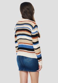 Kötött pulóver bézs, kék, fekete és barna vízszintes csíkokkal. Bordázott szegéllyel és mandzsettákkal, farmer miniszoknyával párosítva.