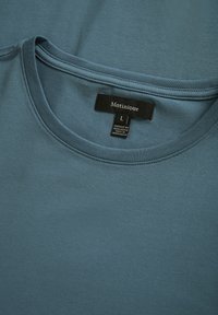 Camiseta de manga corta azul claro hecha de suave tela de algodón, con un cuello redondo y una etiqueta que dice "Matinique" y tamaño "L".